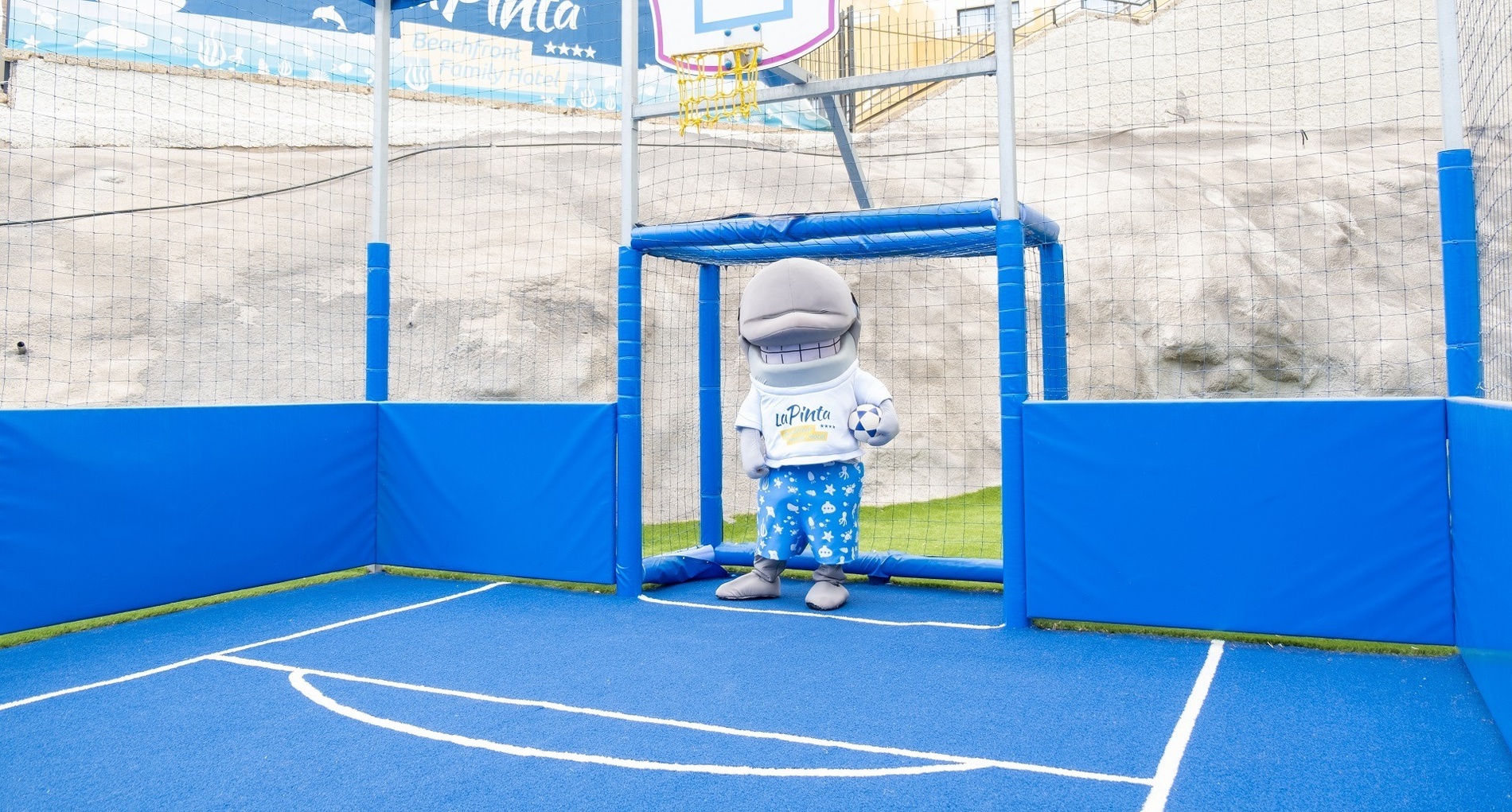 une mascotte de dauphin se tient à côté d' un mur avec des empreintes de mains sur elle