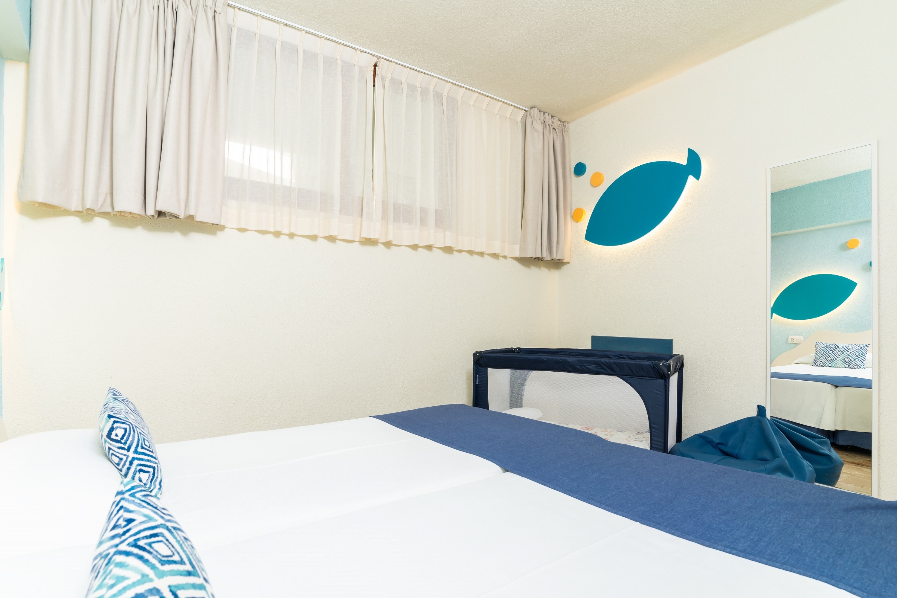 una habitación con una cama y una cuna con un pez pintado en la pared