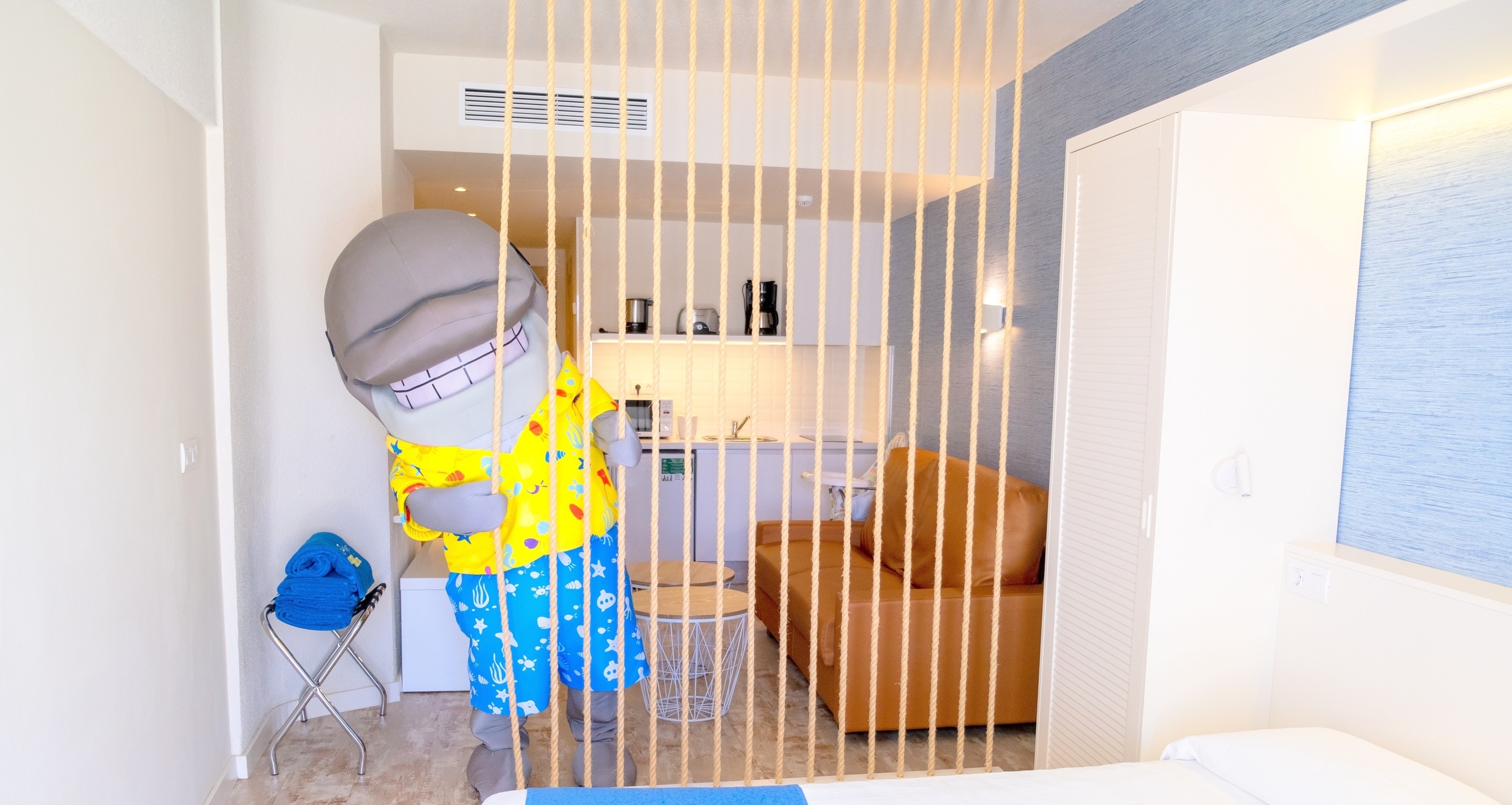 una habitación con una cama azul y un sofá marrón