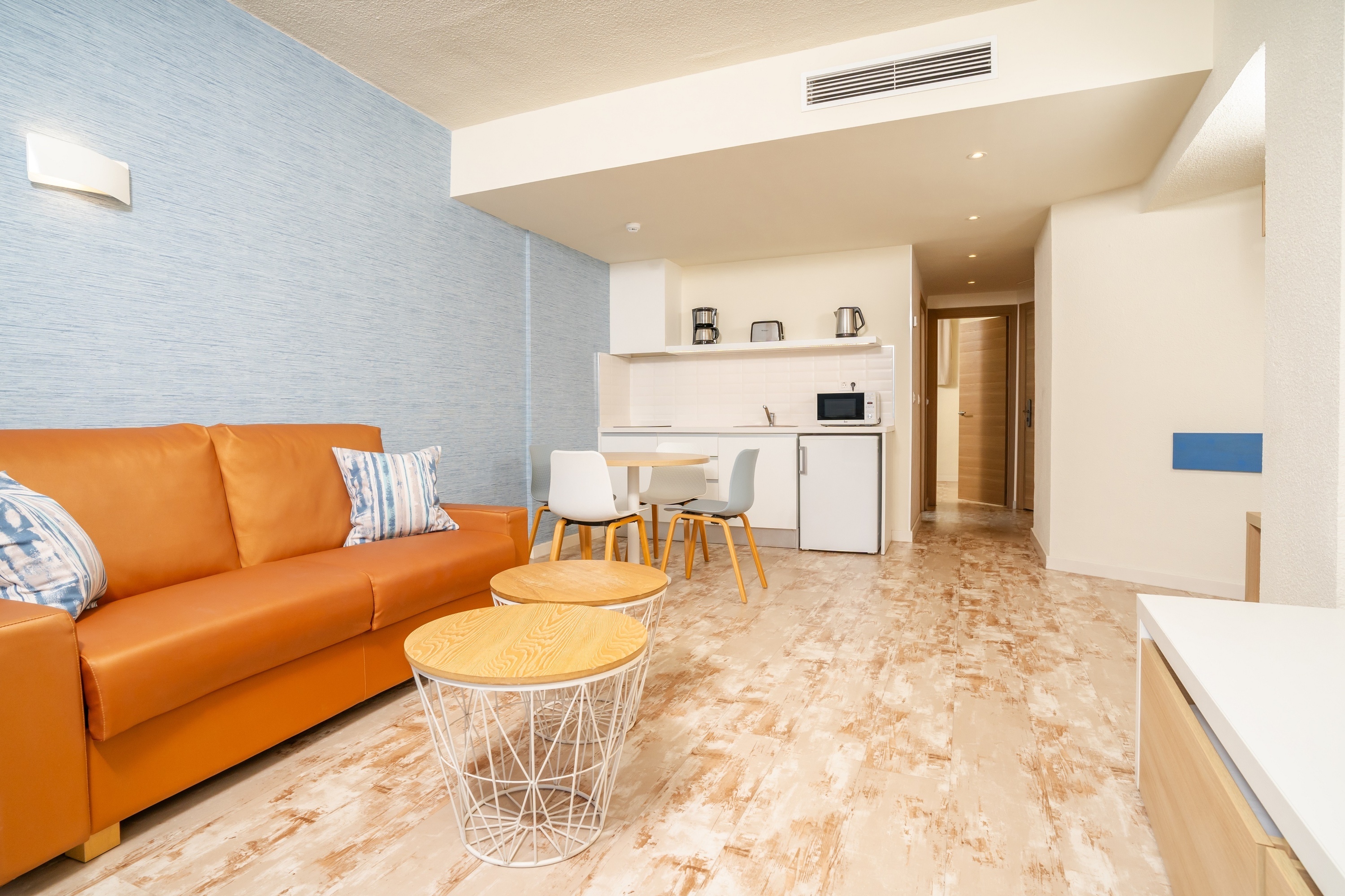 una sala de estar con un sofá marrón y dos mesas