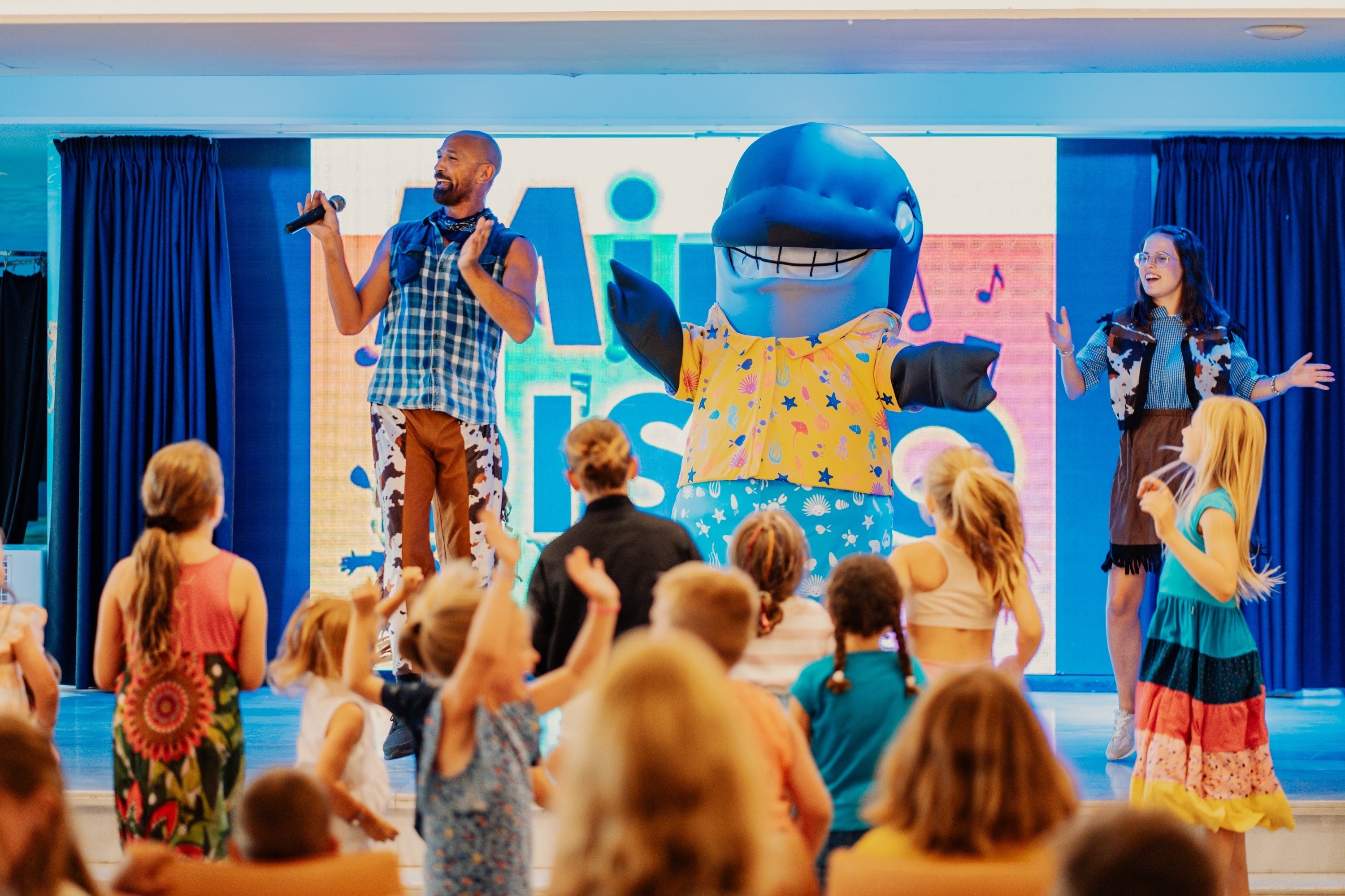un grupo de niños están bailando en un escenario y una niña está sonriendo