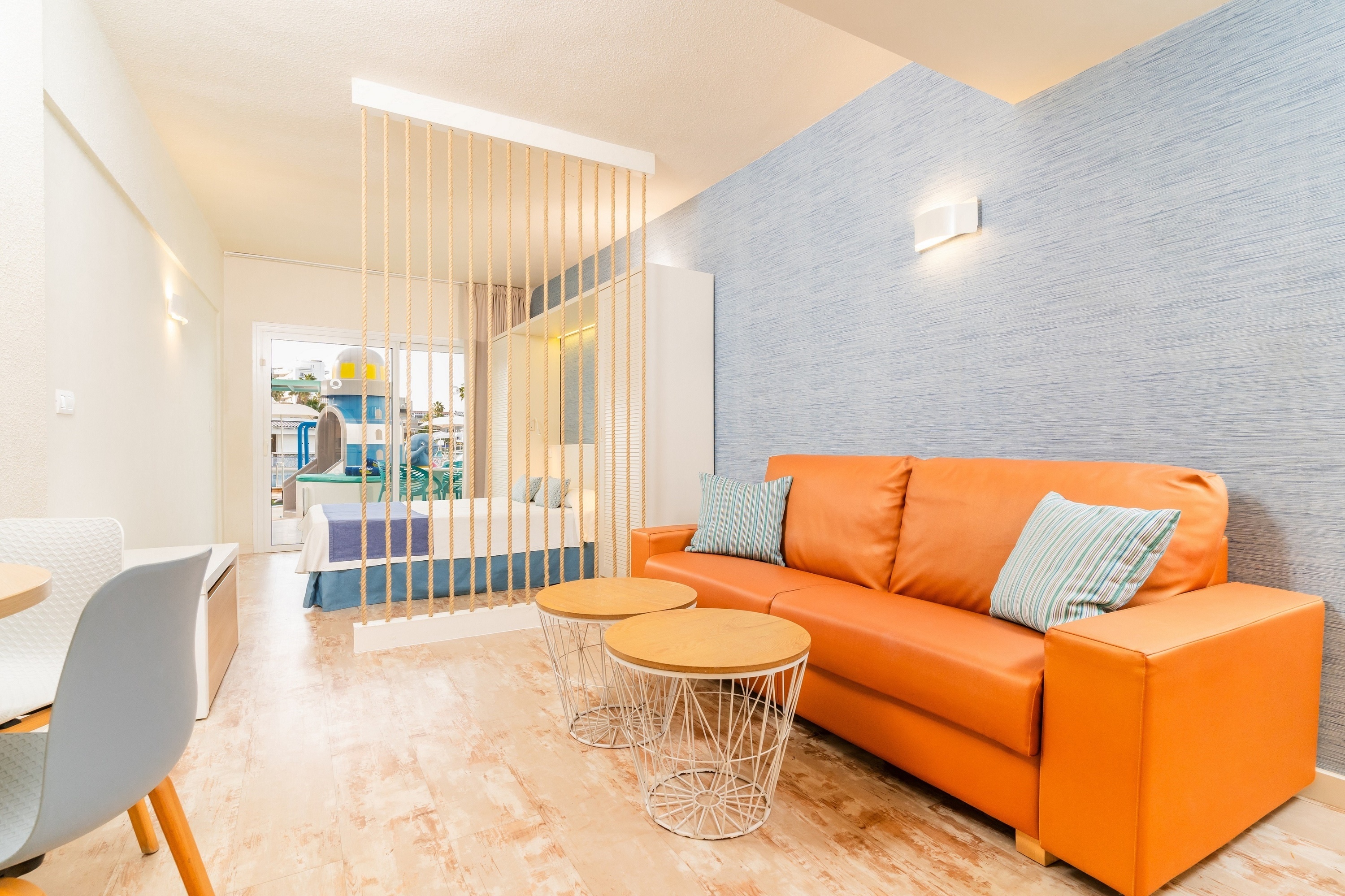 una habitación con una cama azul y un sofá marrón