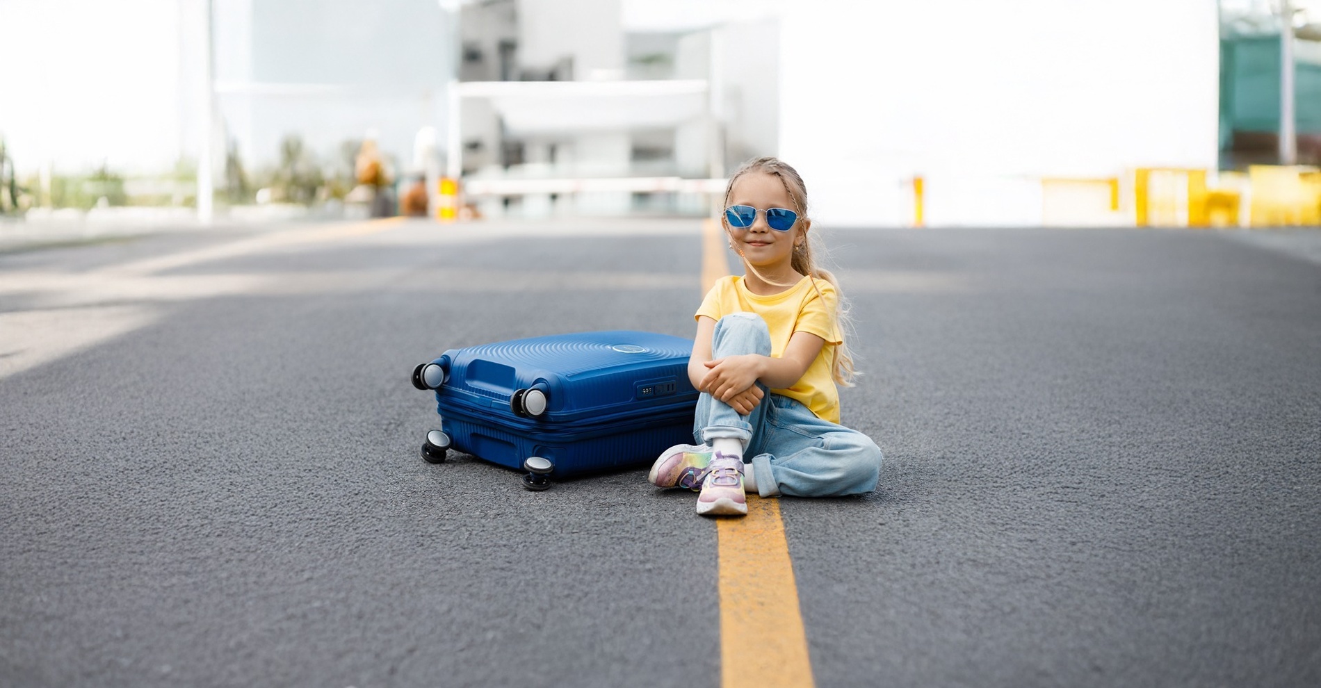 una mujer sostiene una chaqueta marrón mientras camina con una maleta blanca