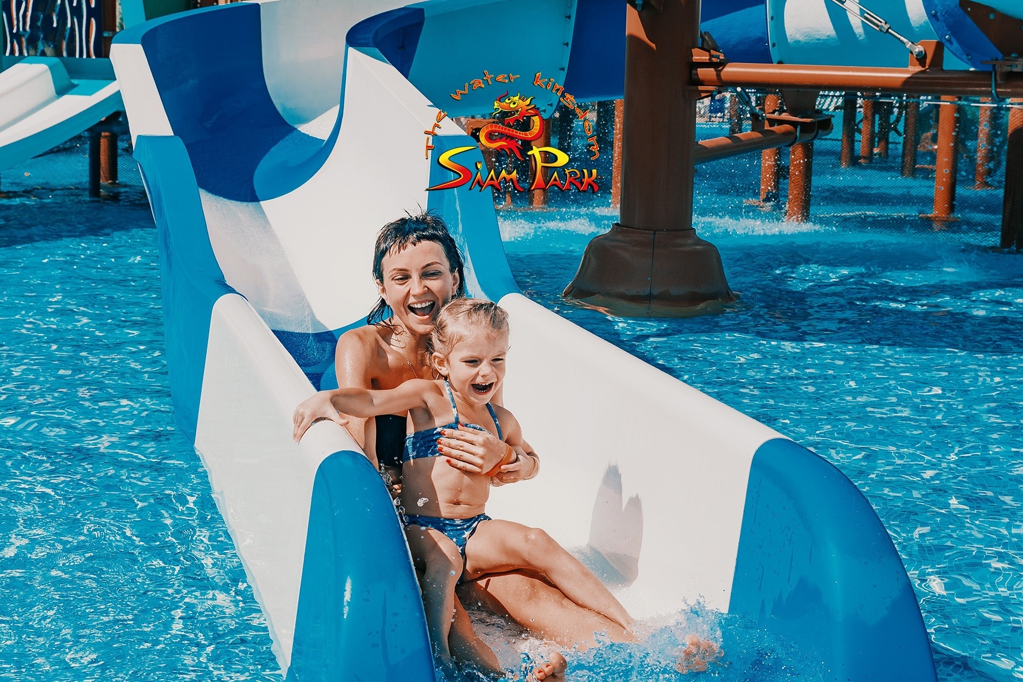 
                                    une femme et une petite fille jouent sur un toboggan dans un parc aquatique