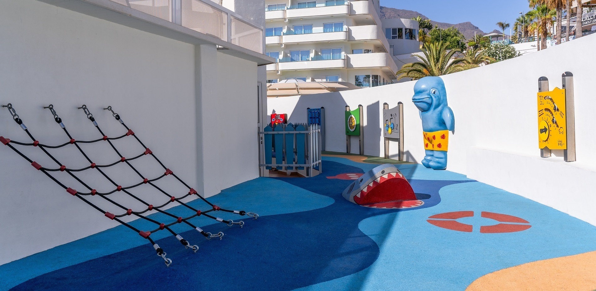 a large swimming pool in front of a hotel with the ocean in the background