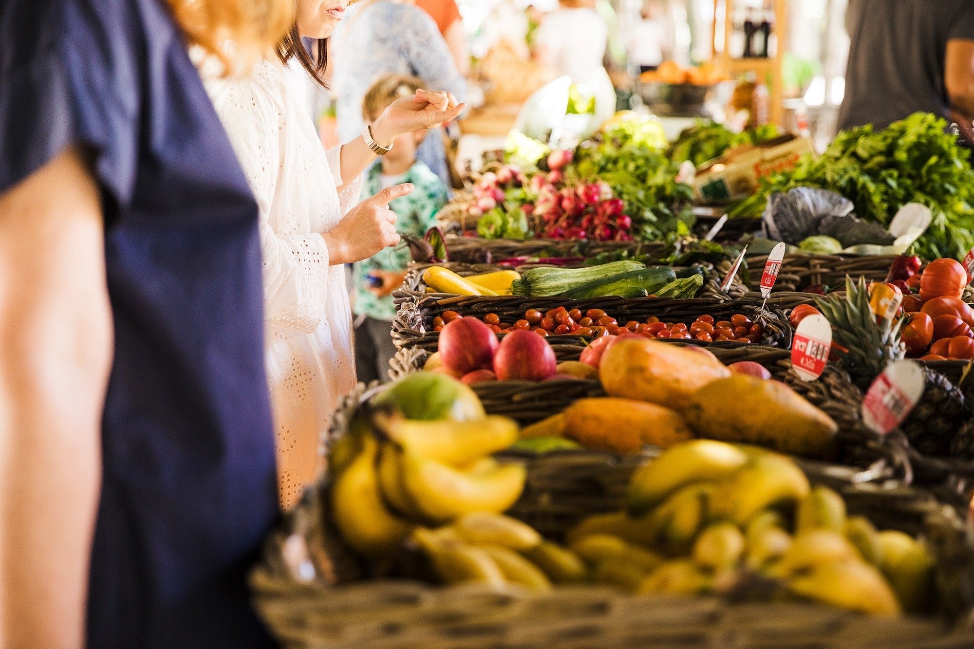 una mujer está mirando un montón de frutas y verduras en un mercado