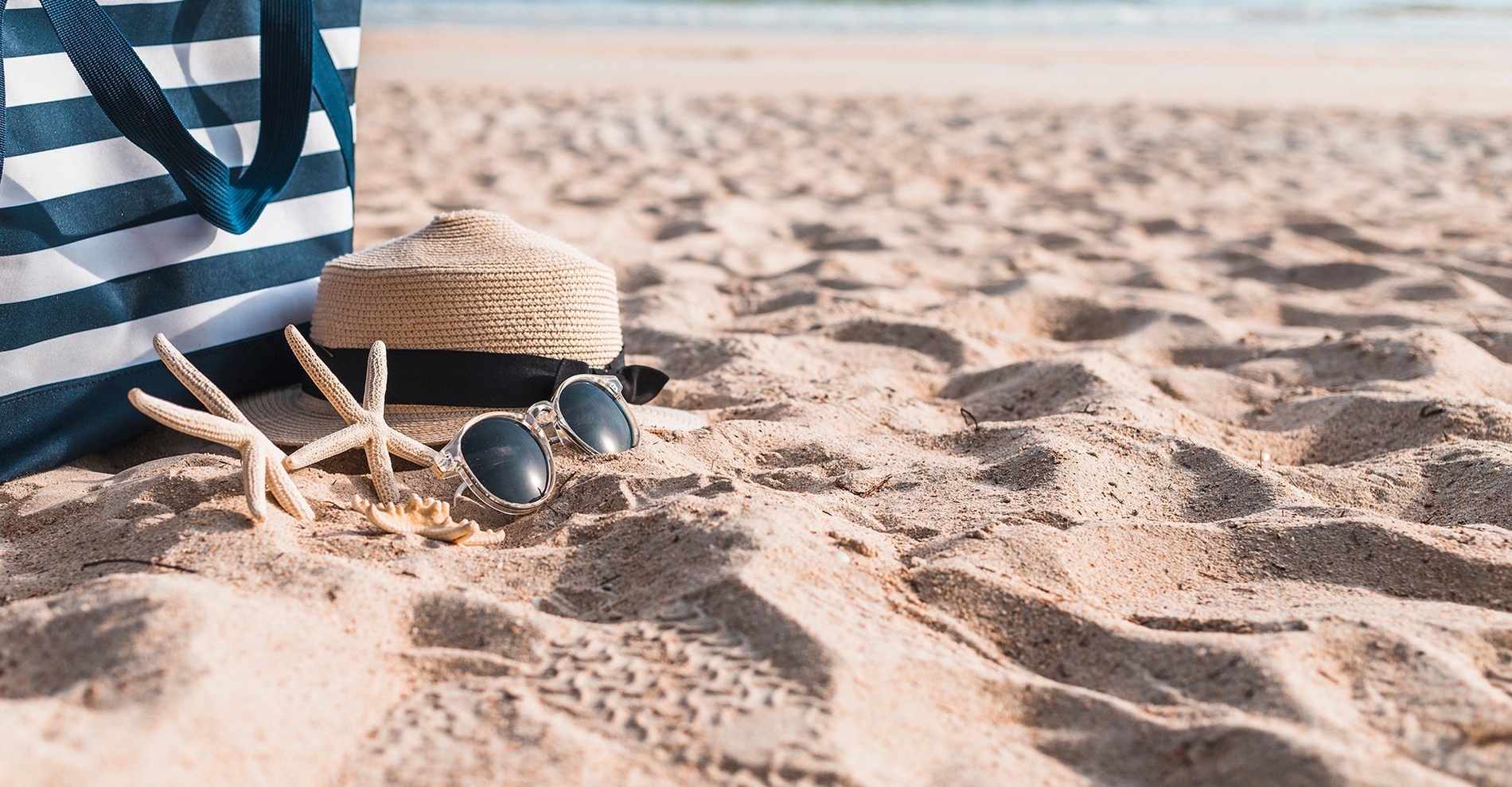 una borsa e occhiali da sole sulla spiaggia