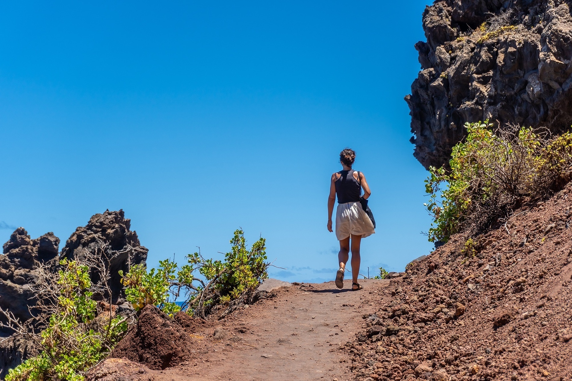 una mujer camina por un sendero junto a un montón de rocas