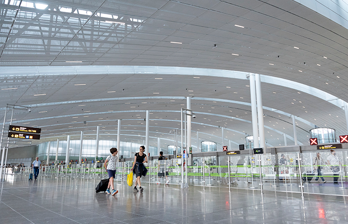 deux personnes marchant dans un terminal d' aéroport avec un panneau indiquant l' arrivée