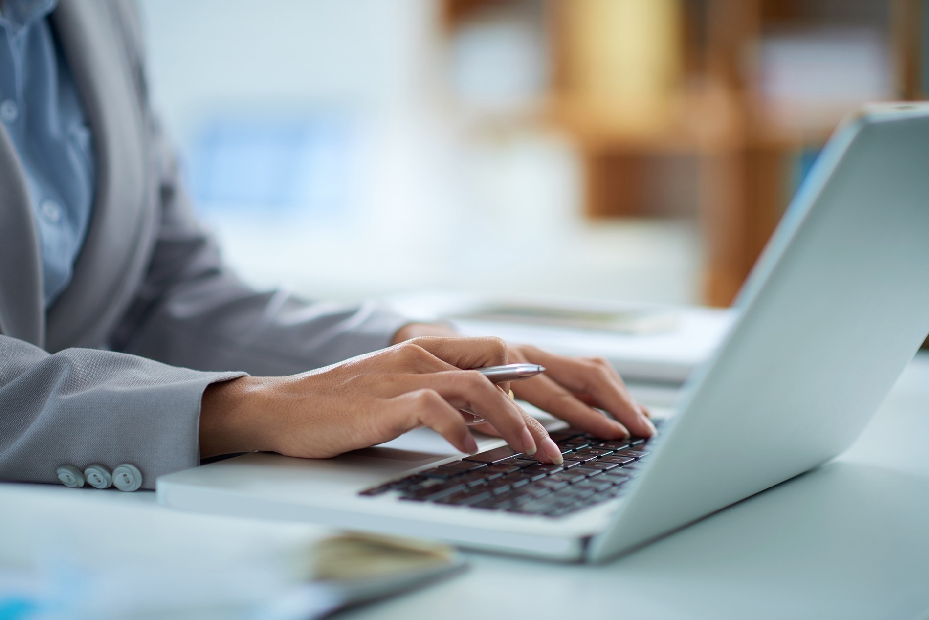 a woman in a suit is typing on a laptop