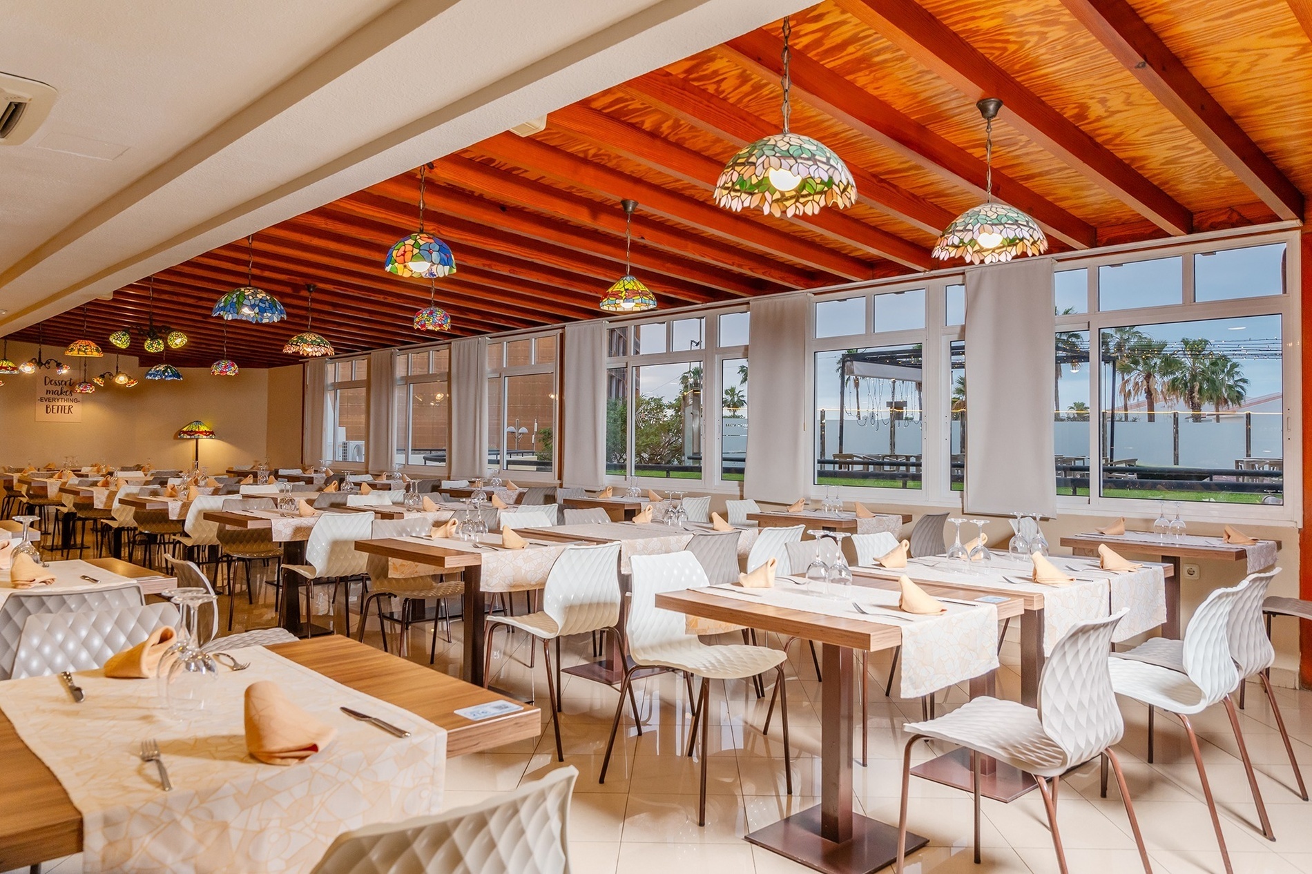 a dining room with tables and chairs and stained glass lamps hanging from the ceiling