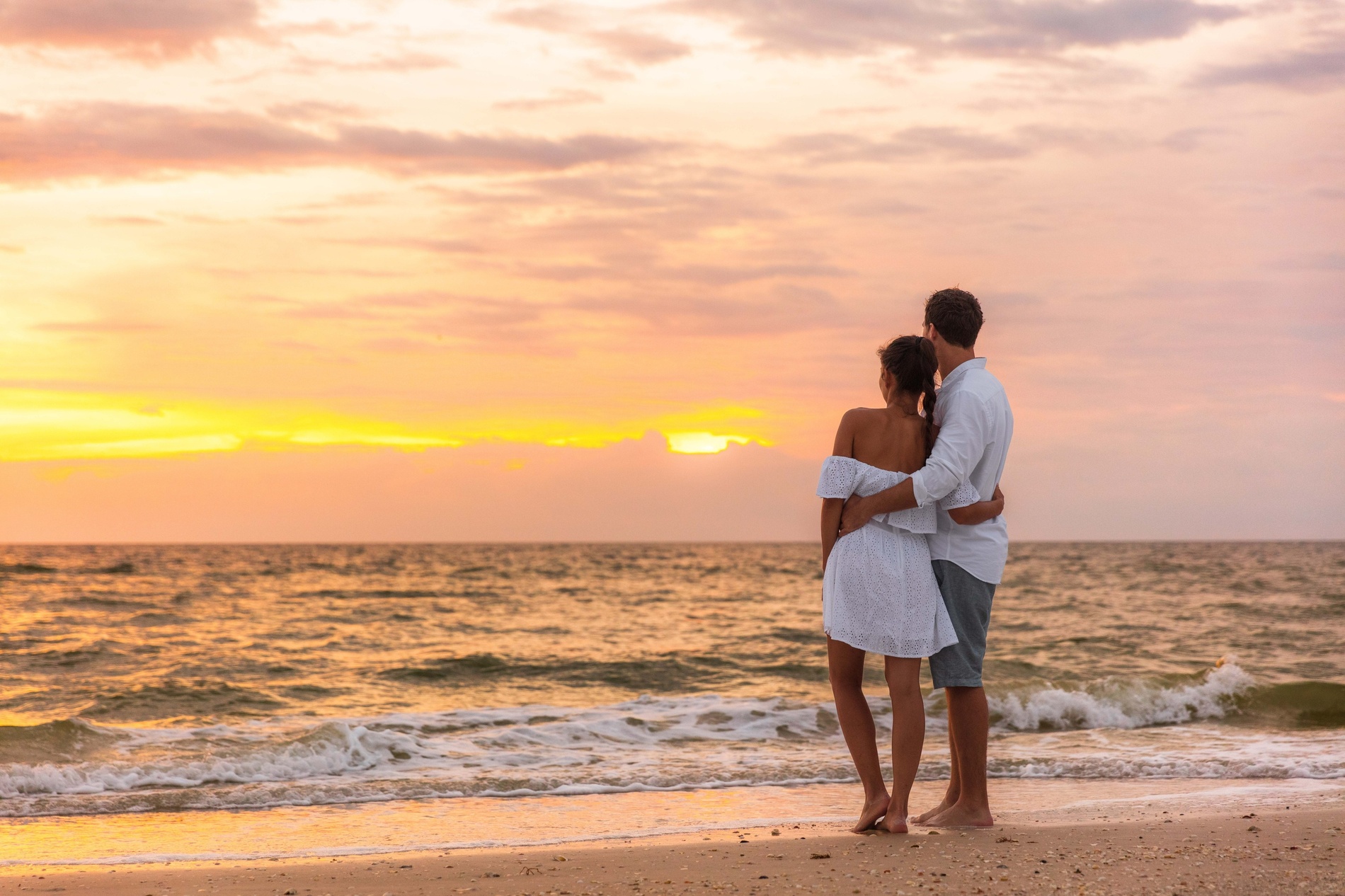 ein Mann und eine Frau stehen am Strand und schauen auf das Meer