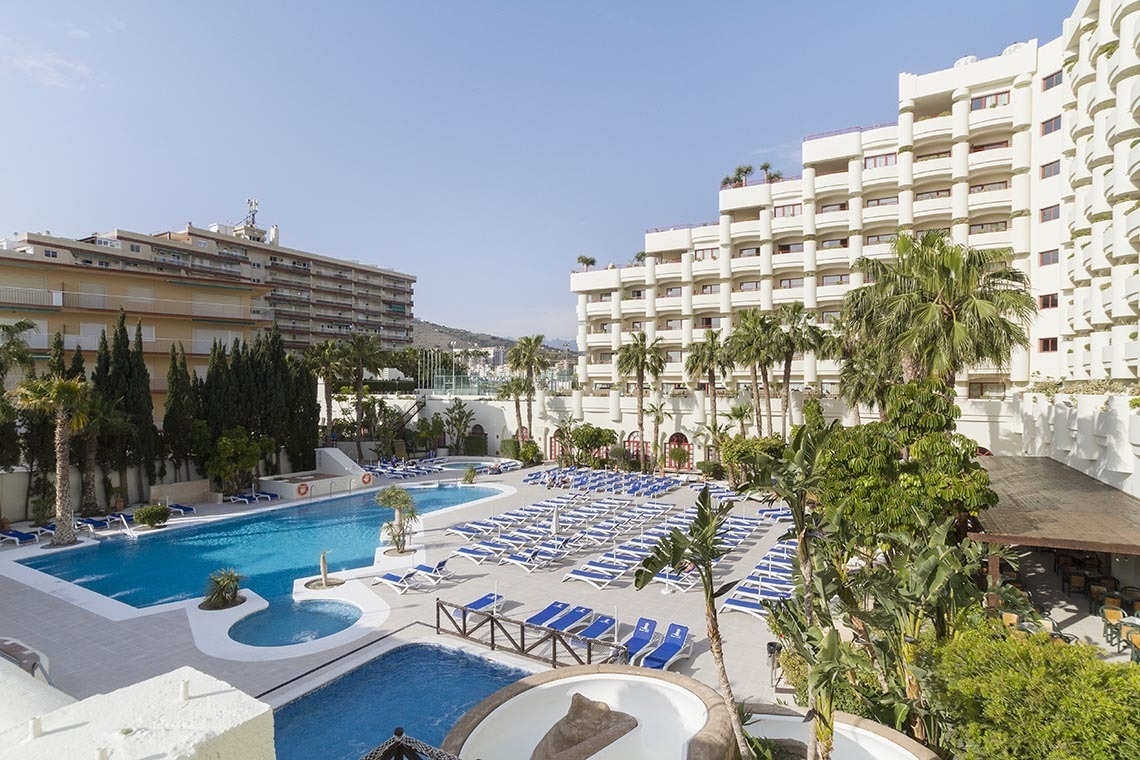 una gran piscina rodeada de sillas y palmeras en un hotel