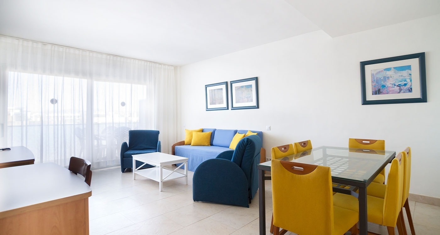 una sala de estar con un sofá azul y una mesa y sillas amarillas