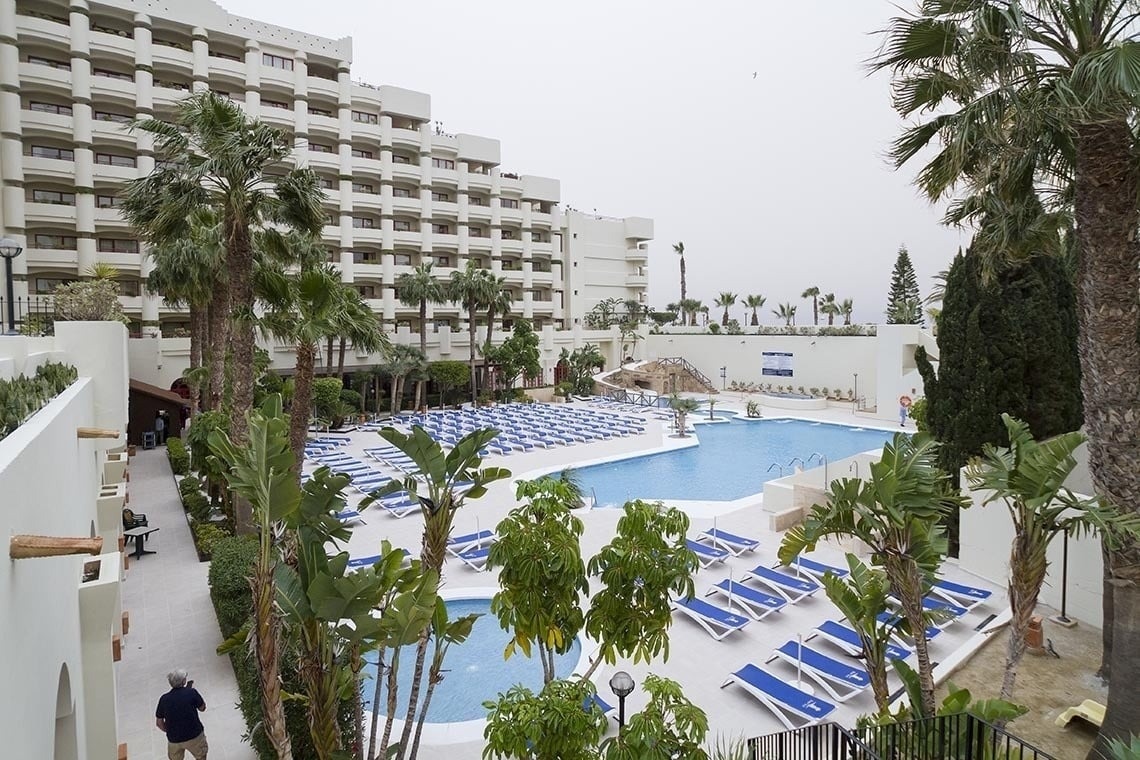 una piscina rodeada de sillas y palmeras en un hotel