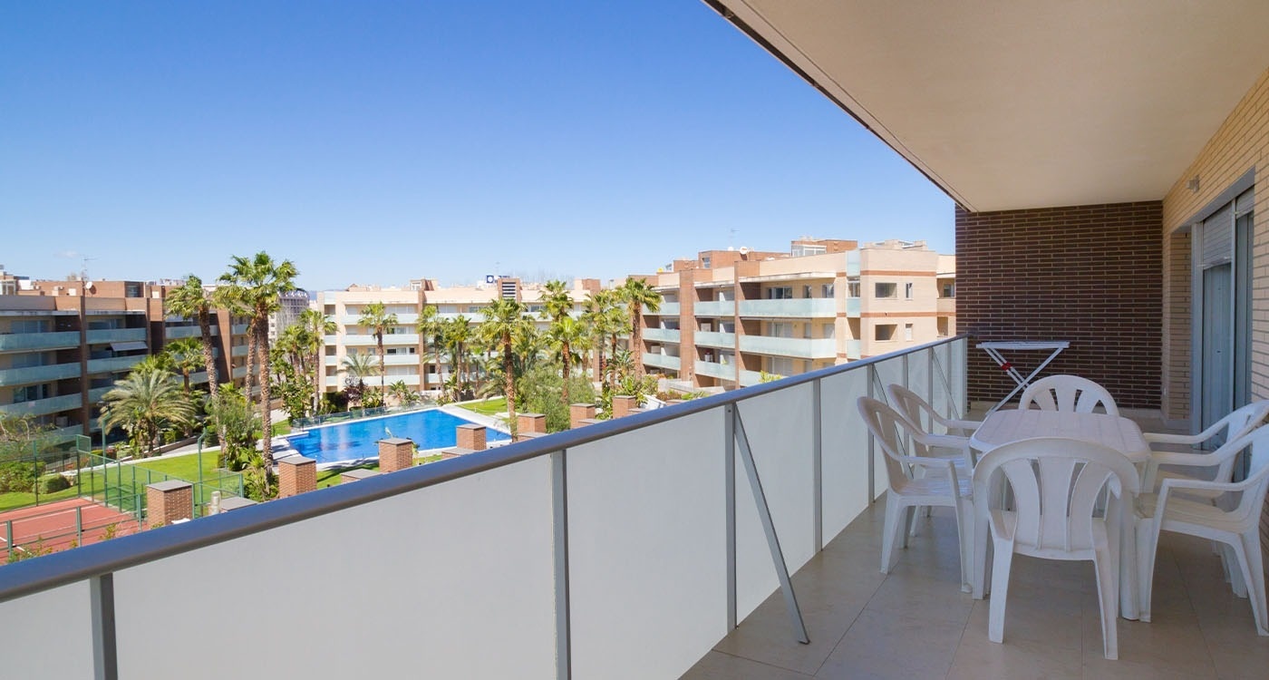 un balcón con una mesa y sillas y una piscina en el fondo