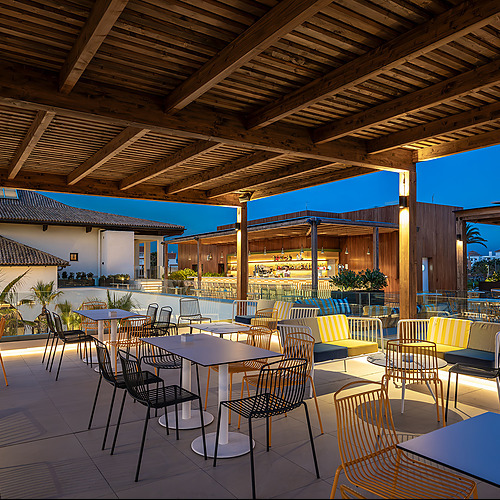 Terraza de hotel con bar y asientos al aire libre, ideal paraImpressive Playa Granada.