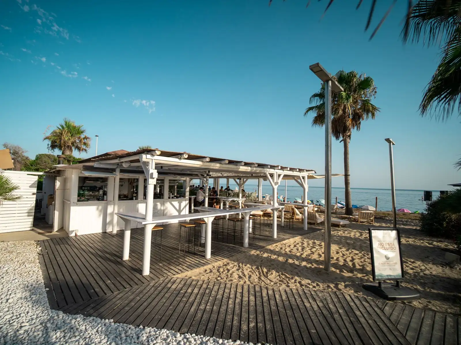 Hoteleigene Strandterrasse mit Tischen, Stühlen und Palmen. Impressive Playa Granada