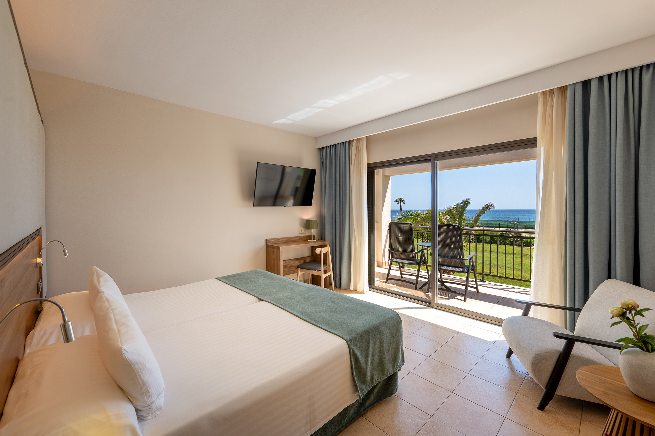 Habitación de hotel con vista al mar, balcón con sillas y cama cómoda. Impressive Playa Granada
