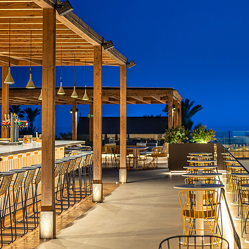 Terraza de restaurante de hotel al aire libre con mesas y sillas, perfecta para Impressive Playa Granada.