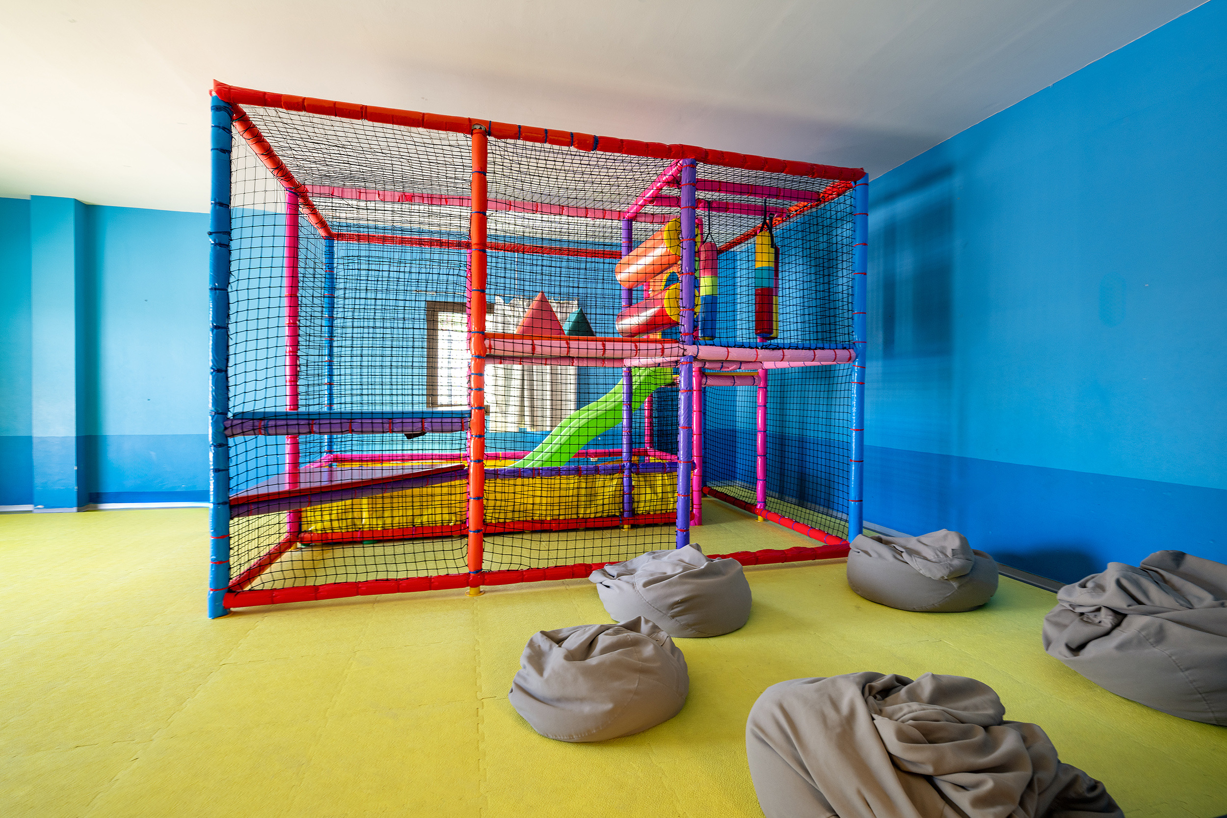 Parque infantil interior colorido con tobogán verde, pelotas y colchonetas, ideal para Impressive Playa Granada.