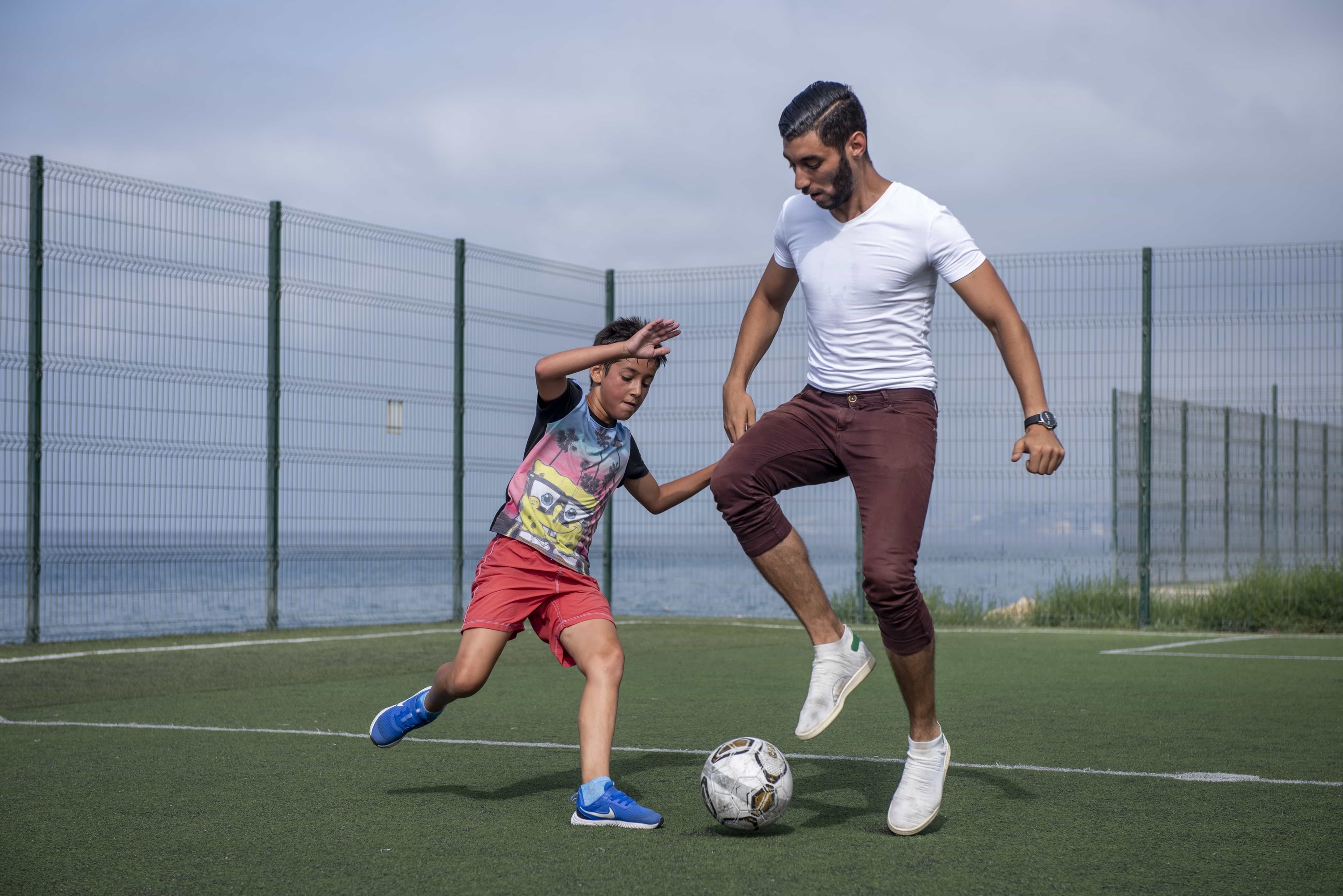 un hombre y un niño juegan al fútbol en un campo
