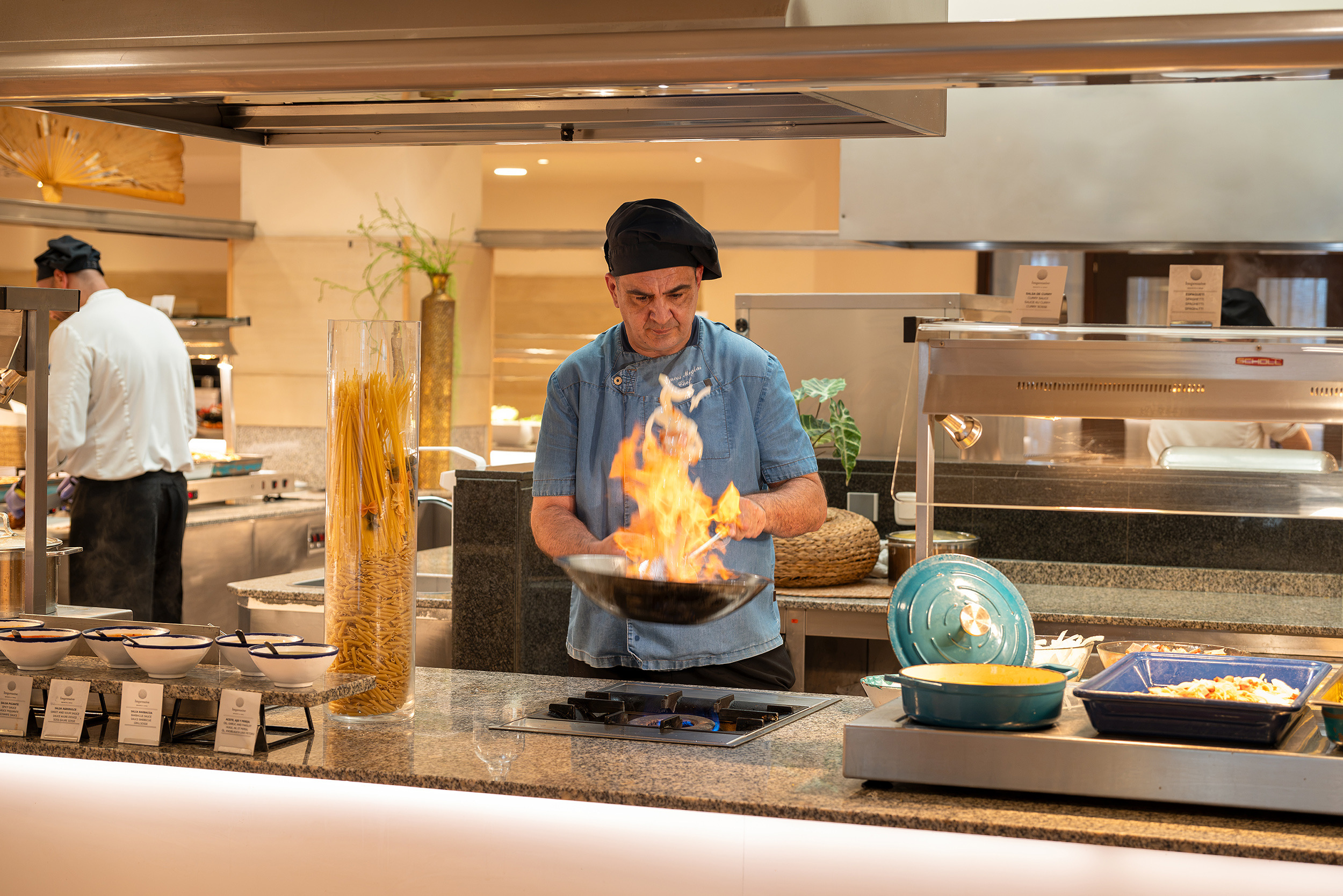 ChefImpressive Playa Granada cocinando con fuego en sartén y botella de licor.