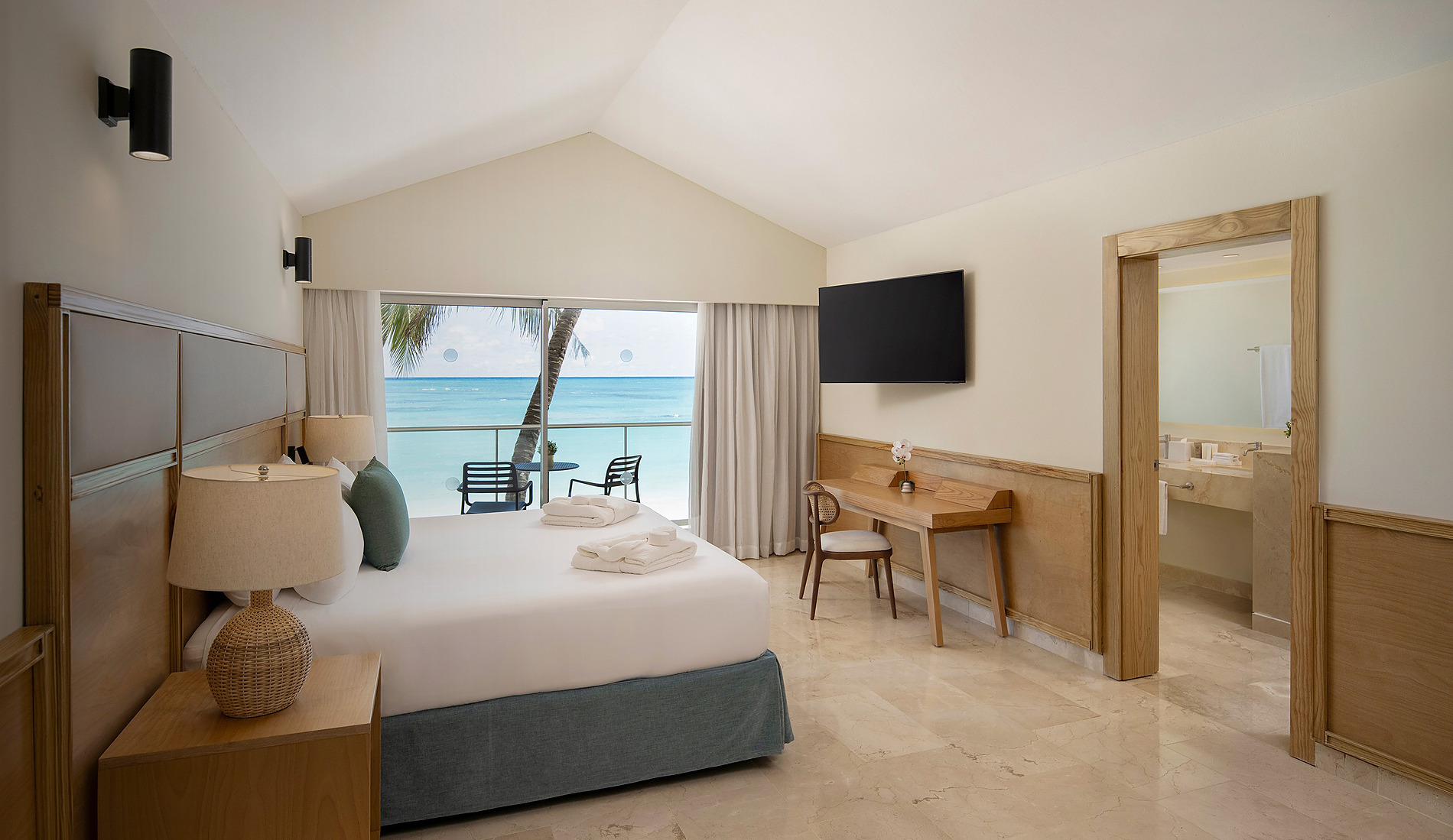 Blaues Schlafsofa, Nachttisch und TV in modernem Hotelzimmer Impressive Royal Punta Cana.