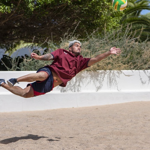 Ein Gast taucht auf einem Beachvolleyballfeld im Impressive Zocos Lanzarote nach dem Ball.