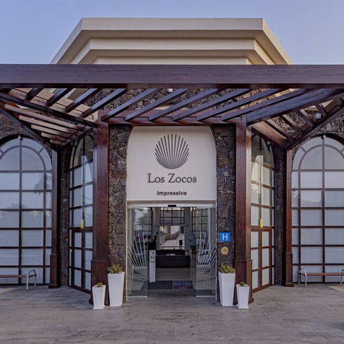 Eingang zum Impressive Zocos Lanzarote Hotel mit eleganter Holzpergola und Steinarchitektur.