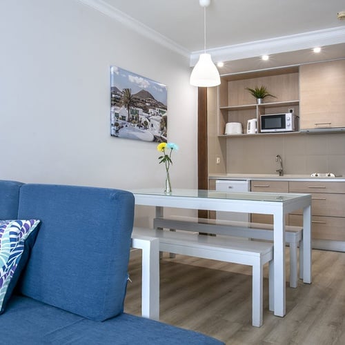 Helles Apartment Wohnzimmer mit blauer Couch, Esstisch, Küchenzeile – Impressive Zocos Lanzarote.