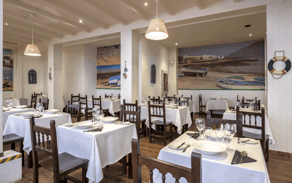 zwei frauen sitzen an einem tisch vor einem restaurant mit delfinen an der wand