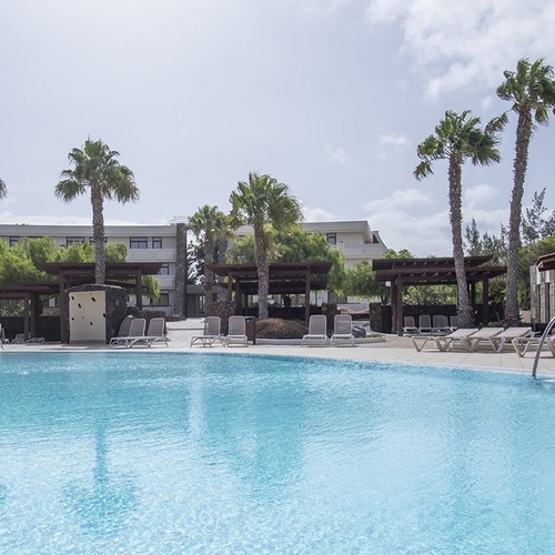 Poolbereich des Impressive Zocos Lanzarote mit großem Schwimmbecken, Palmen, Liegen und Hotelgebäude.