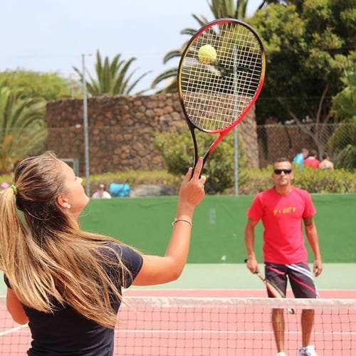 Gäste spielen Tennis im Impressive Zocos Lanzarote. Aktive Urlaubsfreude unter Palmen auf dem Platz.