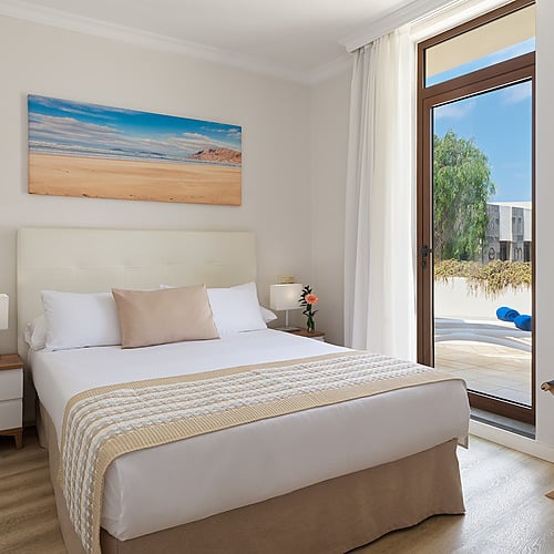 Habitación doble moderna con arte costero y camas confortables en Impressive Zocos Lanzarote.