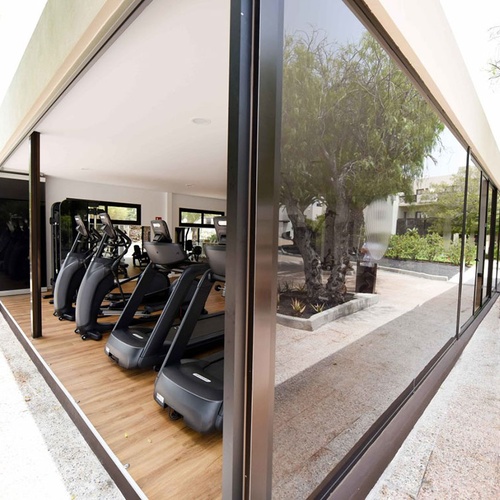 Modernes Hotel-Fitnessstudio im Impressive Zocos Lanzarote mit Laufbändern, großen Fenstern und Blick ins Grüne.