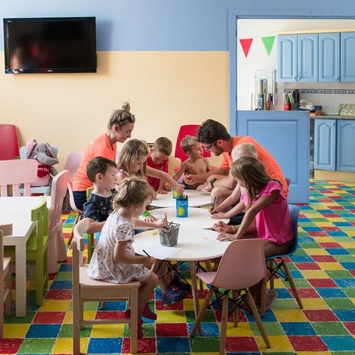 Kinderclub-Aktivitäten im Impressive Zocos Lanzarote: Kinder malen am Tisch mit Betreuern in farbenfrohem Raum.