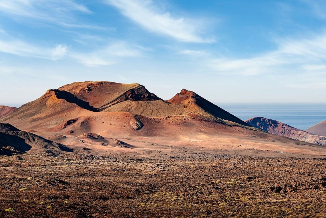 ein großes Gebäude steht auf einem Hügel mit Bäumen und Bergen im Hintergrund