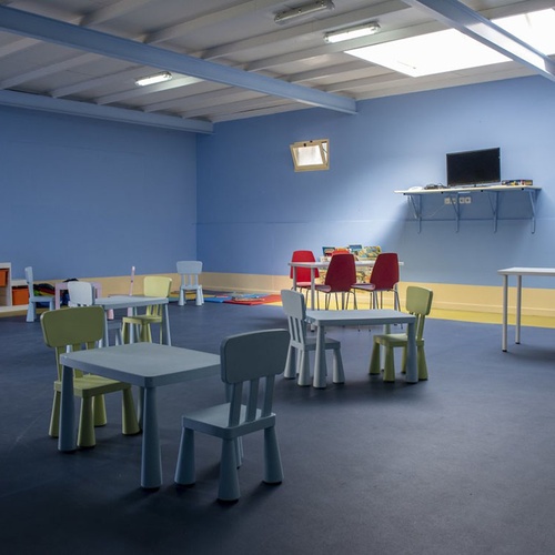 Spielzimmer im Kinderclub des Impressive Zocos Lanzarote mit bunten Tischen und Stühlen.