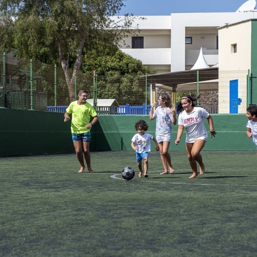 Familie spielt barfuß Fußball auf dem Kunstrasenfeld im Impressive Zocos Lanzarote.