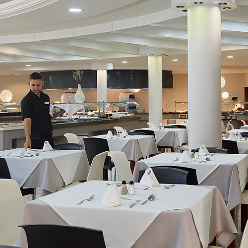 Amplio y moderno restaurante buffet en Impressive Zocos Lanzarote con mesas y estación central de comida.