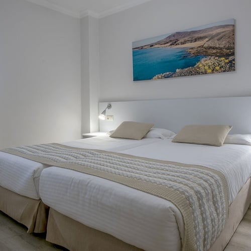 Helles Doppelzimmer im Impressive Zocos Lanzarote mit Meerblick-Wandbild und zwei bequemen Betten.