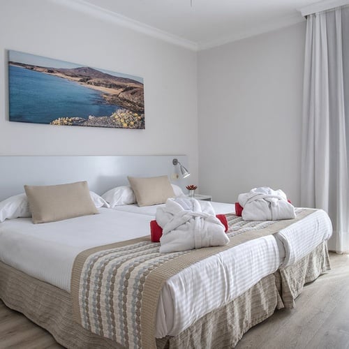 Komfortables Twin-Zimmer im Impressive Zocos Lanzarote mit Meerblickbild, Bademänteln und viel Tageslicht.