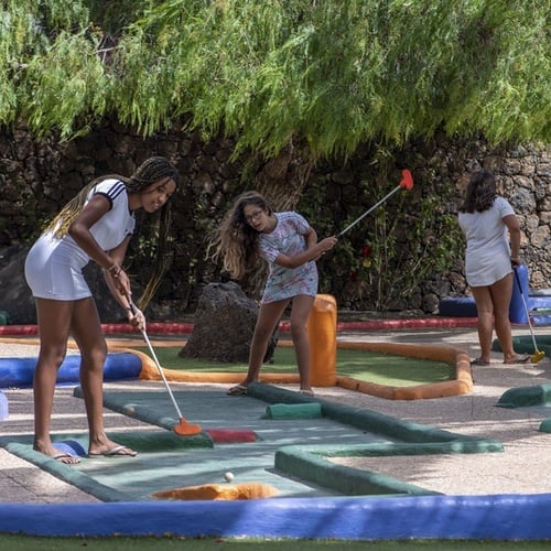 Fröhliche Familie spielt Minigolf im Impressive Zocos Lanzarote, perfekte Urlaubsaktivität.