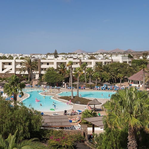 Impressive Zocos Lanzarote: Weitläufige Poollandschaft mit Palmen unter blauem Himmel.