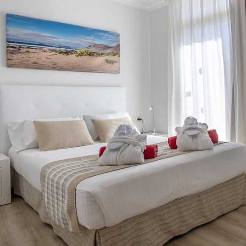 Komfortables Hotelzimmer im Impressive Zocos Lanzarote mit Doppelbett, Strandbild und moderner Einrichtung.