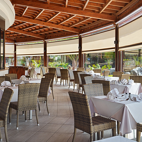 Elegante restaurante en Impressive Zocos Lanzarote con mesas puestas y barra de madera.