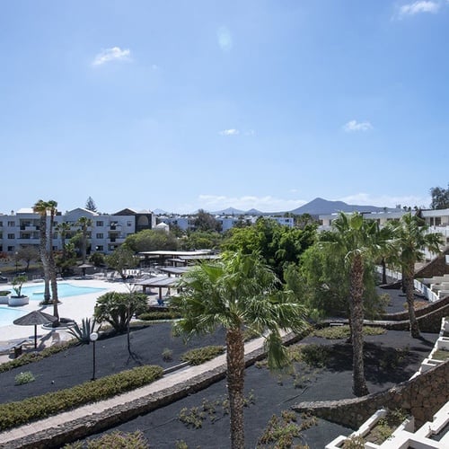 Impressive Zocos Lanzarote: Sonniger Poolbereich, Palmen & vulkanische Architektur.