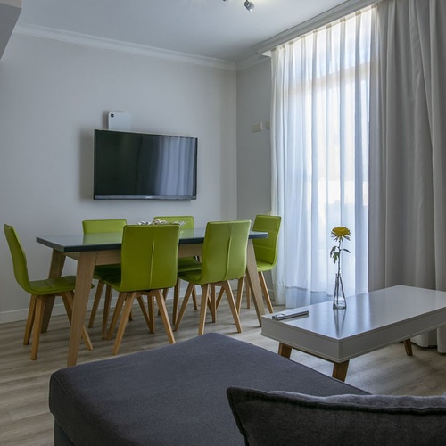 Moderner Wohn-/Essbereich im Impressive Zocos Lanzarote mit hellen Stühlen, TV und gemütlichem Schlafzimmerblick.