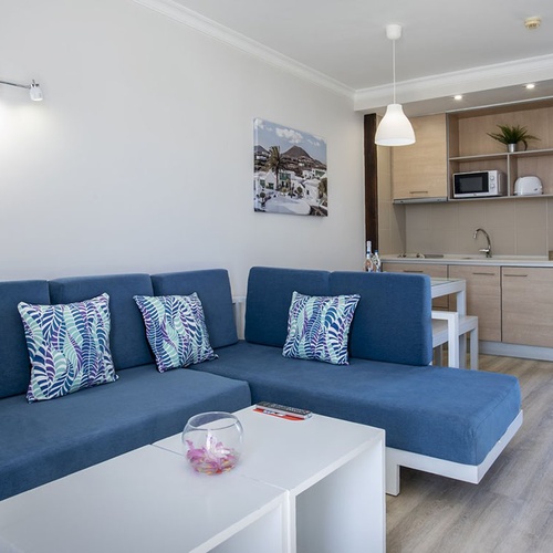 Helles Apartment mit blauem Ecksofa, gemusterten Kissen & Küchenzeile im Impressive Zocos Lanzarote.